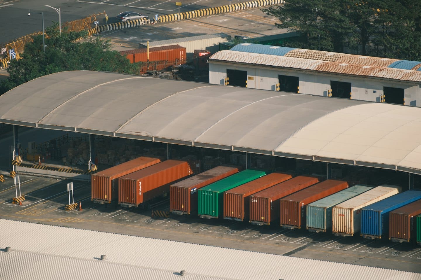 Kontejnery se zbožím uspořádané v rušném logistickém a přepravním centru.